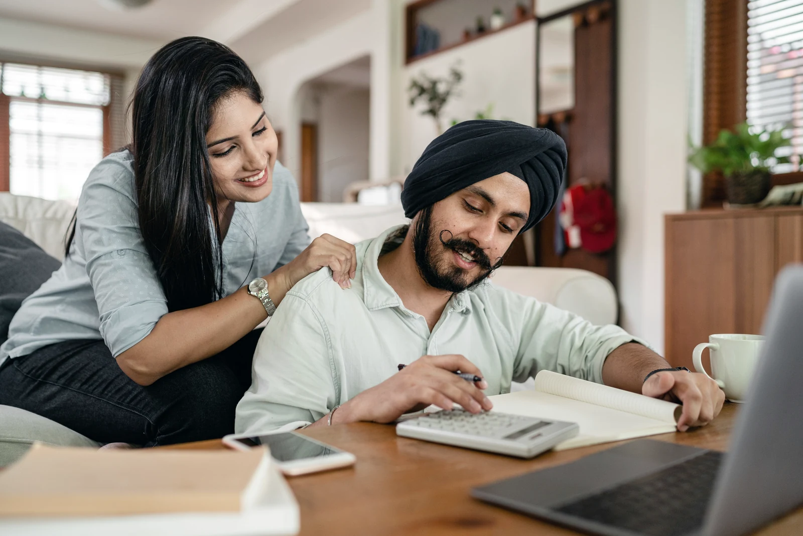 A couple sitting together at a bright kitchen table looking at a smartphone while working through their Super Visa insurance questions